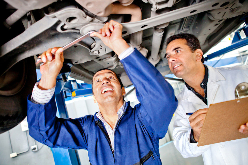 Professional mechanics looking under a car while repairing it