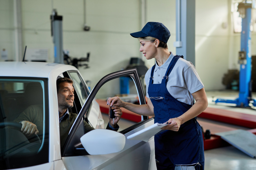 female attendant at an auto shop giving keys to cars